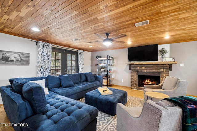 living room featuring wooden ceiling, french doors, light wood-type flooring, ceiling fan, and a brick fireplace