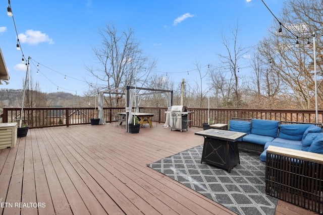 wooden terrace featuring an outdoor living space with a fire pit and area for grilling