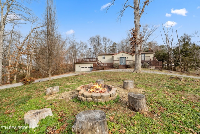 view of yard featuring an outdoor fire pit, a garage, and a wooden deck