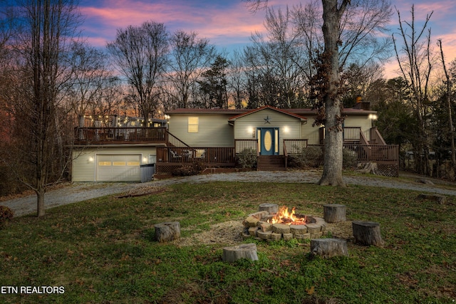 view of front of home featuring a yard, a wooden deck, an outdoor fire pit, and a garage