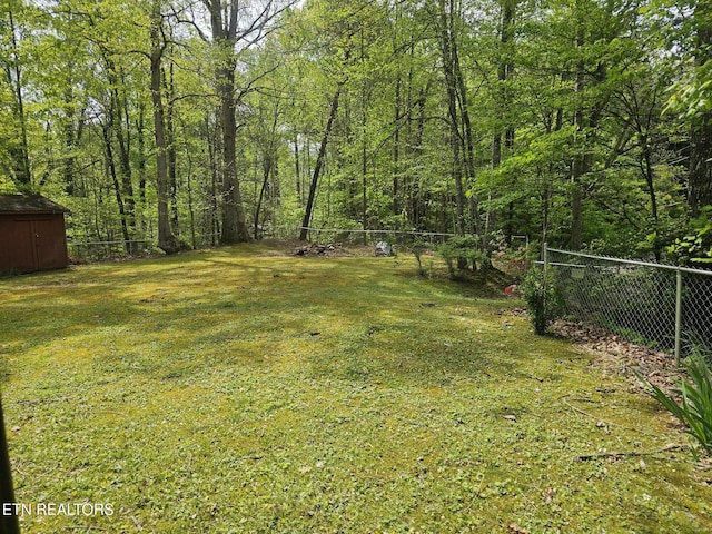 537 Gatlin Dr, Gatlinburg, TN 37738 - view of yard featuring an outdoor structure, a shed, a forest view, and a fenced backyard