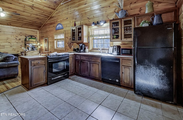 kitchen with black appliances, wood ceiling, light tile patterned flooring, and wood walls