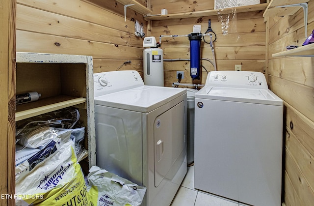 washroom featuring washing machine and clothes dryer, wood walls, and light tile patterned floors