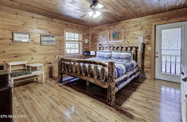 bedroom featuring wood ceiling, wood walls, light wood-type flooring, ceiling fan, and access to exterior