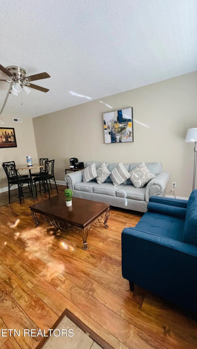 living room featuring a textured ceiling, ceiling fan, and hardwood / wood-style floors