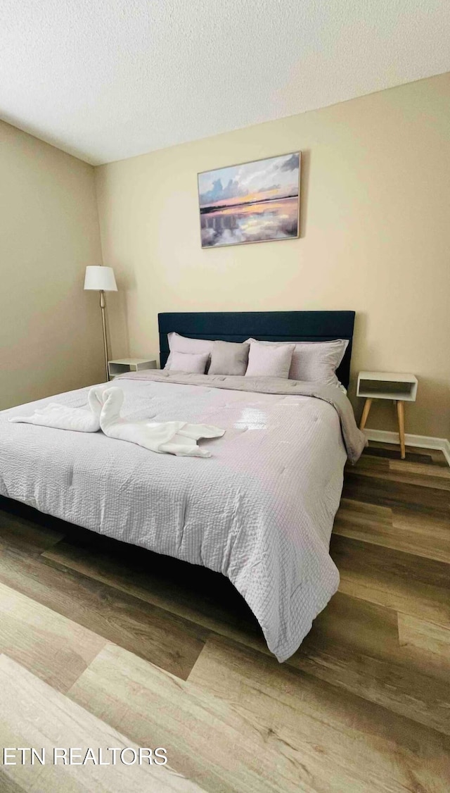 bedroom with a textured ceiling and hardwood / wood-style flooring