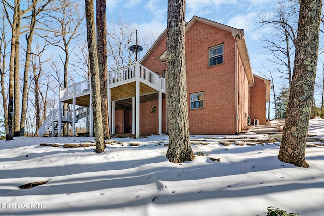 snow covered back of property featuring a wooden deck