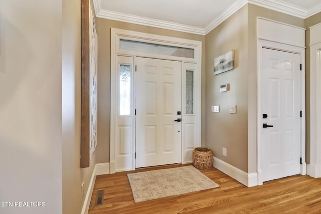 foyer with ornamental molding and light hardwood / wood-style flooring