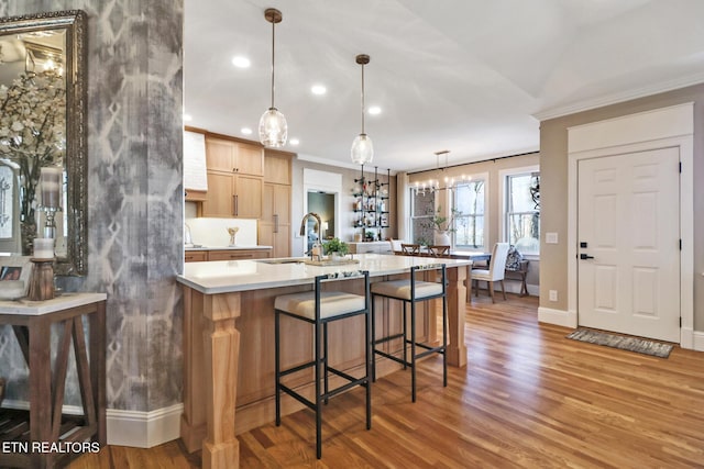 kitchen featuring hanging light fixtures, wood-type flooring, sink, and light brown cabinets