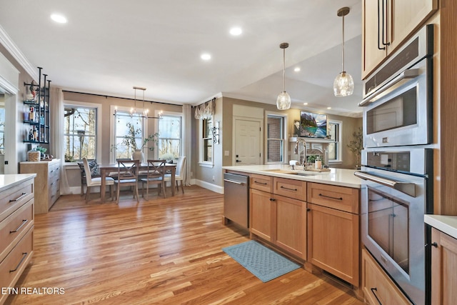 kitchen with pendant lighting, sink, ornamental molding, and stainless steel dishwasher