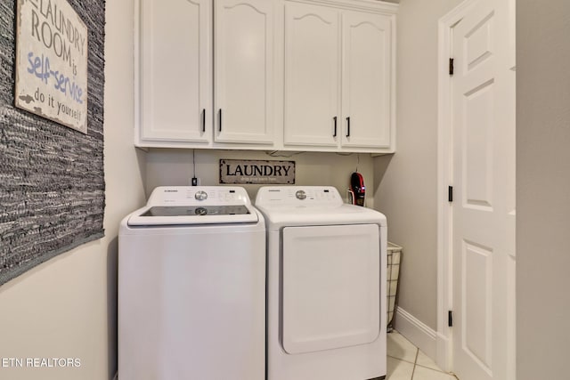 clothes washing area featuring cabinets, washer and dryer, and light tile patterned floors