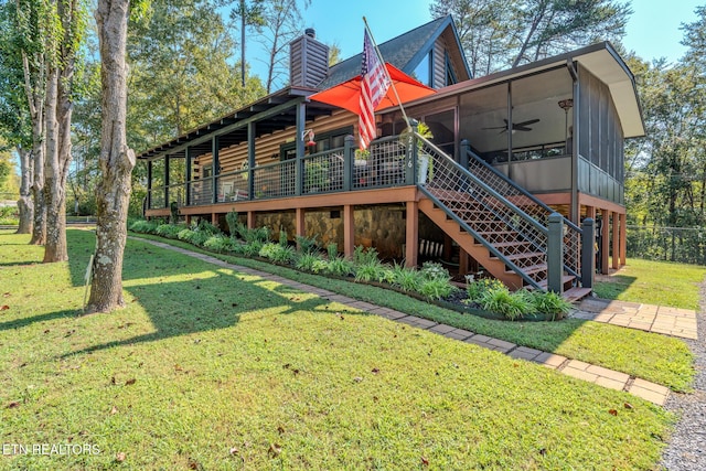 rear view of house with ceiling fan, a deck, a sunroom, and a yard