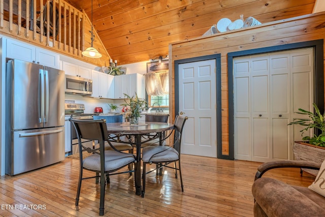 dining room with wood ceiling, light hardwood / wood-style flooring, wooden walls, and high vaulted ceiling