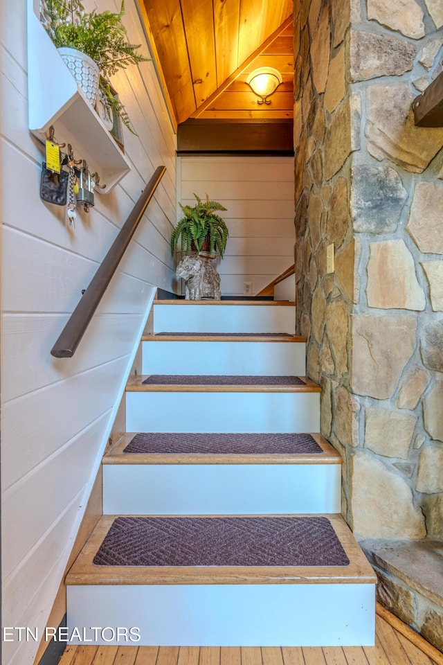 stairway with wood ceiling, wooden walls, and hardwood / wood-style flooring