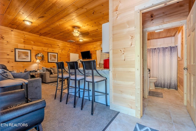 tiled living room featuring wood walls and wooden ceiling