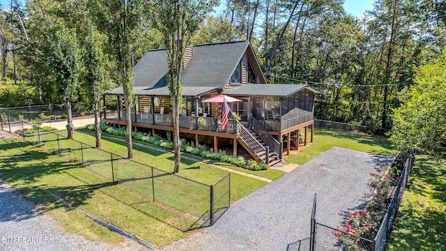 back of house with a wooden deck, a sunroom, and a yard