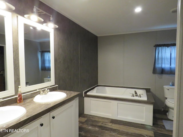 bathroom with a garden tub, toilet, double vanity, and a sink