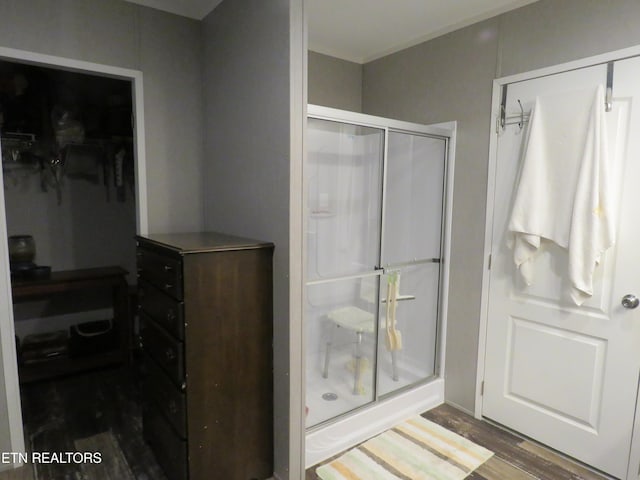 full bath with a spacious closet, a stall shower, and wood finished floors