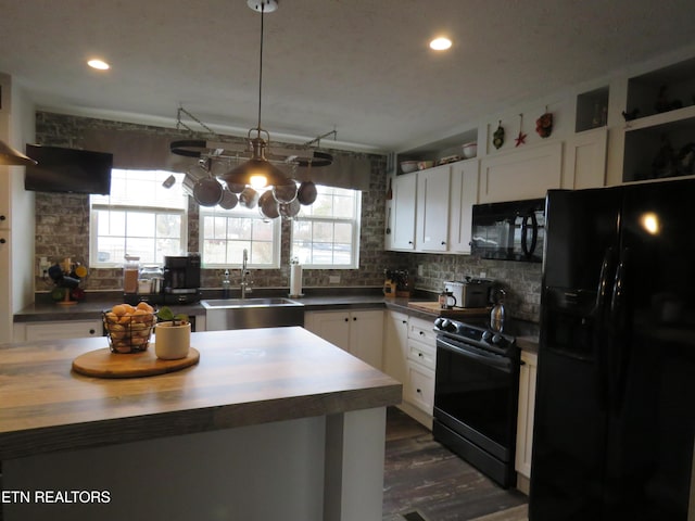 kitchen featuring a healthy amount of sunlight, a sink, decorative backsplash, black appliances, and white cabinetry