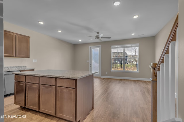 kitchen with light wood-type flooring, ceiling fan, stainless steel dishwasher, and a center island