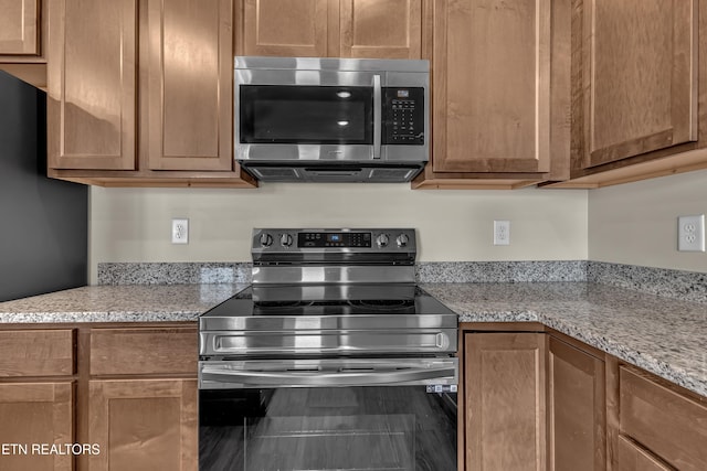 kitchen with light stone countertops and appliances with stainless steel finishes