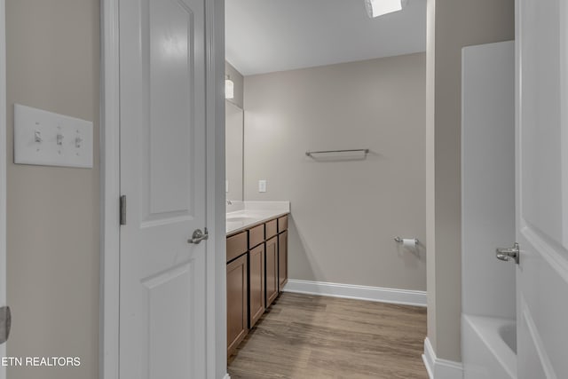 bathroom featuring wood-type flooring, vanity, and a washtub