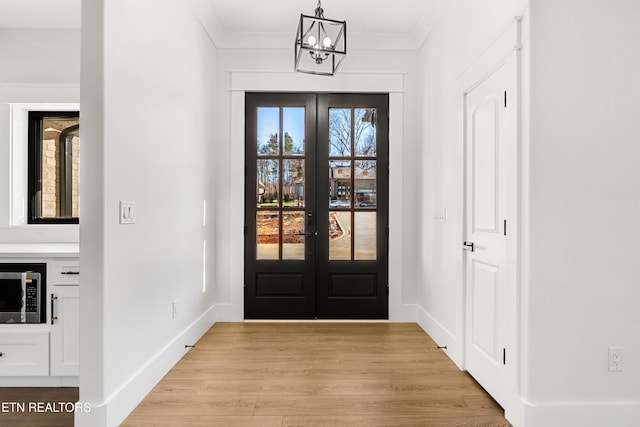 foyer with a notable chandelier, french doors, and ornamental molding