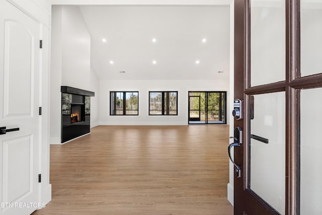 unfurnished living room with a fireplace, high vaulted ceiling, and light hardwood / wood-style floors