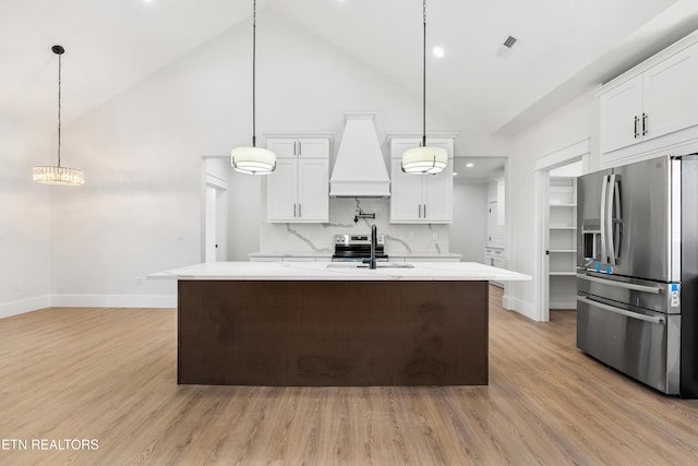 kitchen with premium range hood, pendant lighting, stainless steel refrigerator with ice dispenser, white cabinets, and tasteful backsplash