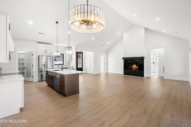 kitchen featuring stainless steel appliances, high vaulted ceiling, a multi sided fireplace, white cabinetry, and dark brown cabinets