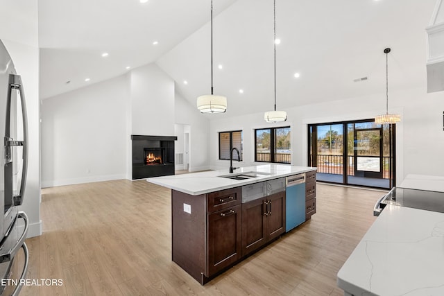 kitchen featuring sink, decorative light fixtures, a large island, a multi sided fireplace, and appliances with stainless steel finishes