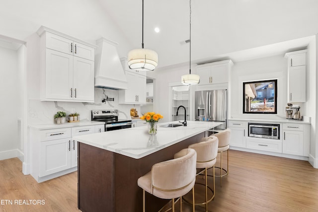 kitchen with stainless steel appliances, hanging light fixtures, custom range hood, white cabinets, and sink