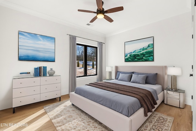 bedroom featuring ceiling fan, light wood-type flooring, and crown molding