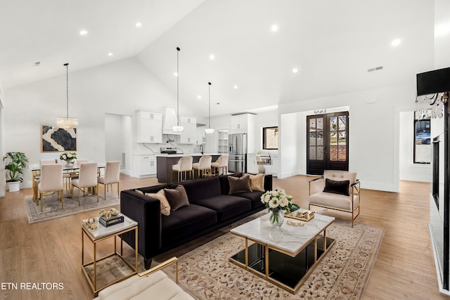 living room with light hardwood / wood-style floors, french doors, and high vaulted ceiling