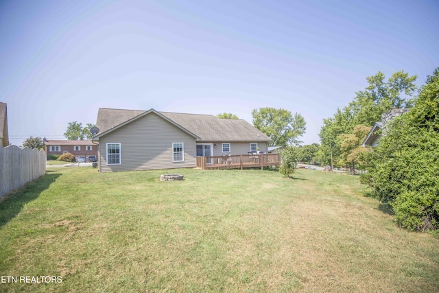 back of house with a wooden deck, an outdoor fire pit, and a lawn