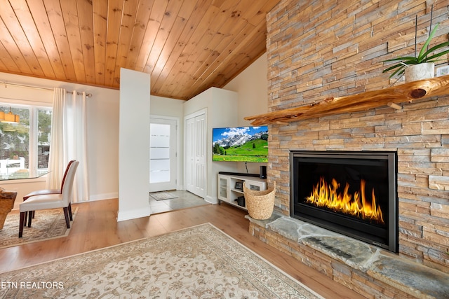 living room with hardwood / wood-style flooring, wood ceiling, and a stone fireplace