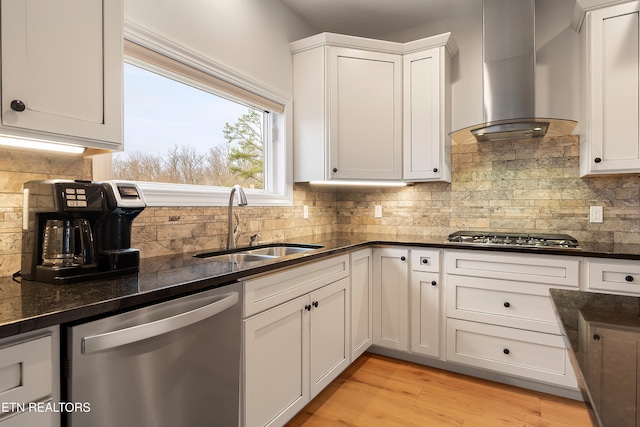 kitchen with stainless steel appliances, sink, white cabinetry, decorative backsplash, and wall chimney range hood