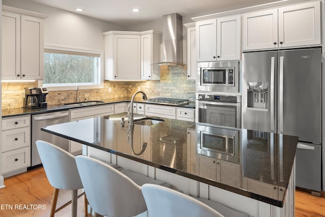 kitchen featuring sink, a breakfast bar area, wall chimney exhaust hood, and appliances with stainless steel finishes