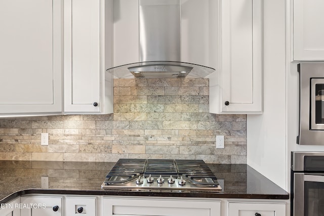 kitchen with white cabinets, exhaust hood, appliances with stainless steel finishes, and decorative backsplash