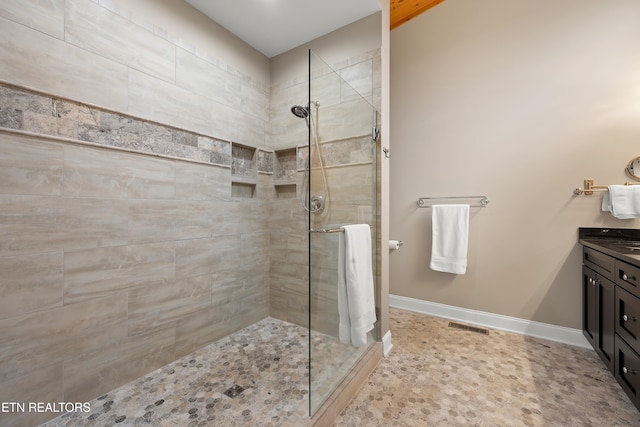 bathroom with tiled shower and vanity