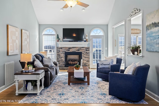 living room with wood finished floors, visible vents, baseboards, a fireplace, and vaulted ceiling