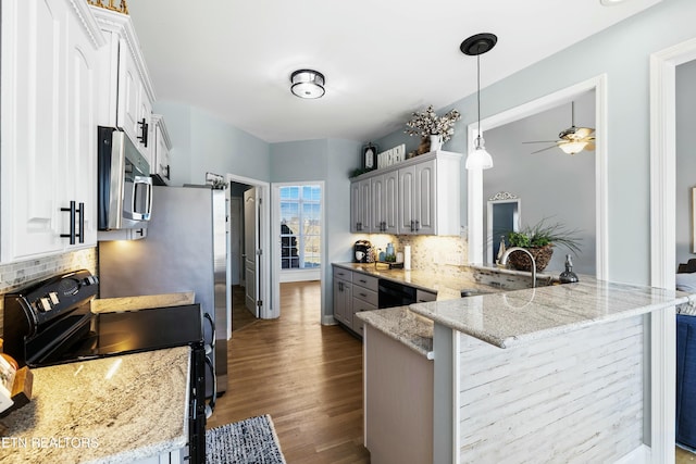 kitchen featuring black / electric stove, dark wood finished floors, a peninsula, stainless steel microwave, and tasteful backsplash