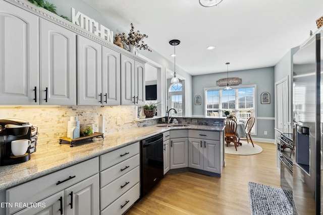 kitchen featuring a sink, stainless steel fridge, black dishwasher, light wood-type flooring, and backsplash