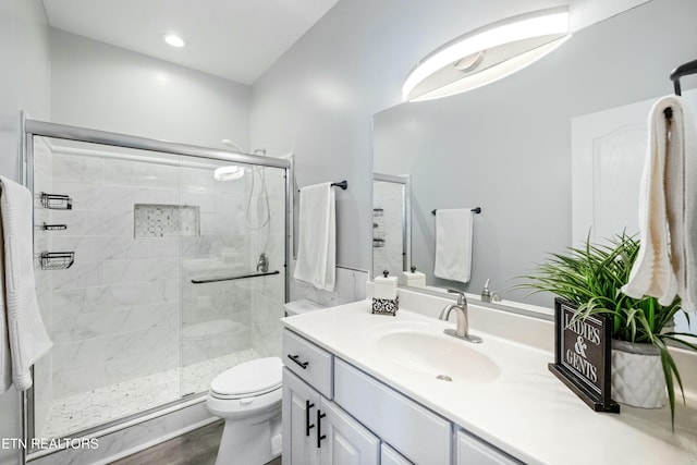 bathroom with vanity, a shower stall, and toilet