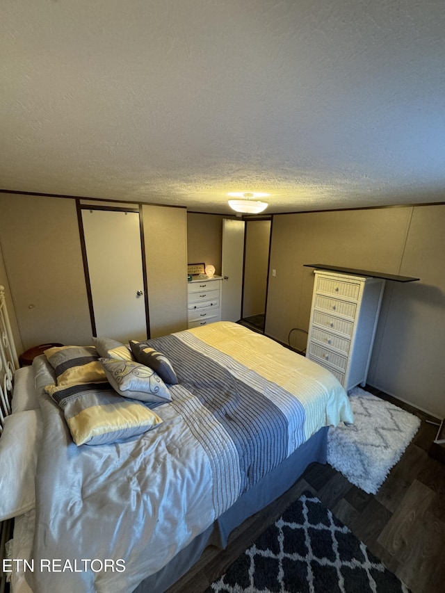 bedroom with a textured ceiling and dark hardwood / wood-style floors