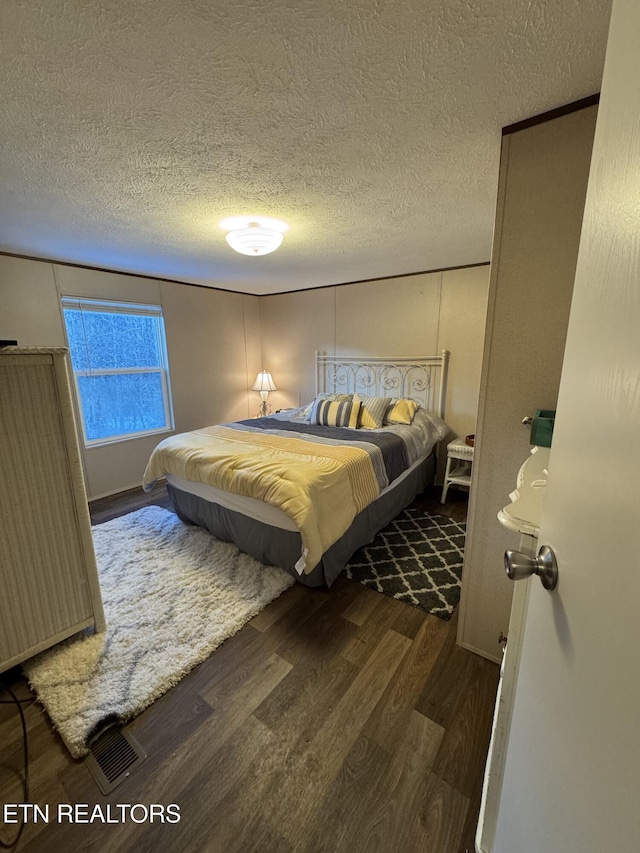 bedroom with a textured ceiling and dark hardwood / wood-style floors