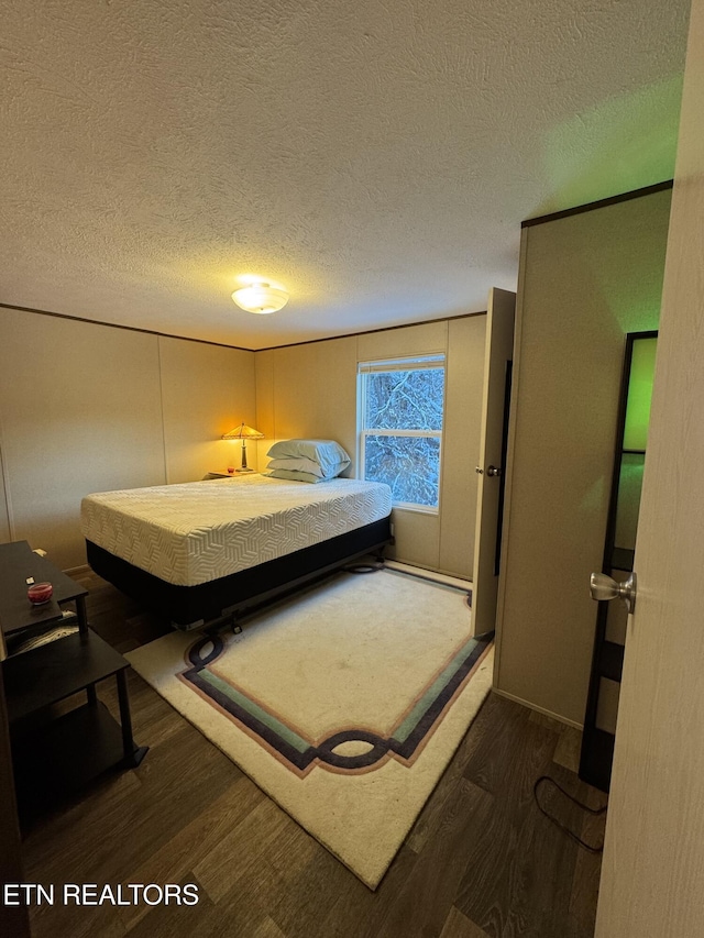 bedroom with dark hardwood / wood-style flooring and a textured ceiling