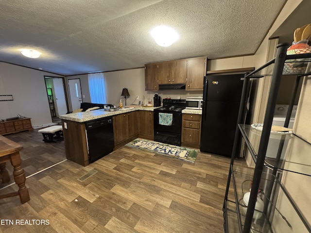 kitchen featuring a textured ceiling, dark wood-type flooring, black appliances, and kitchen peninsula