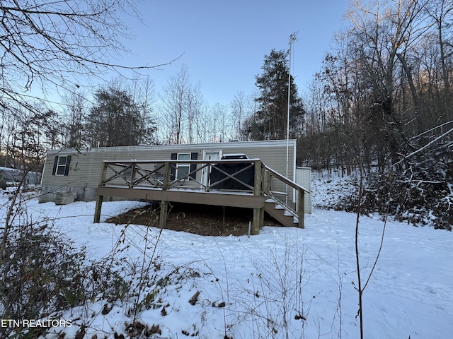 snow covered rear of property featuring a wooden deck