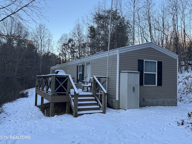 snow covered back of property with a wooden deck